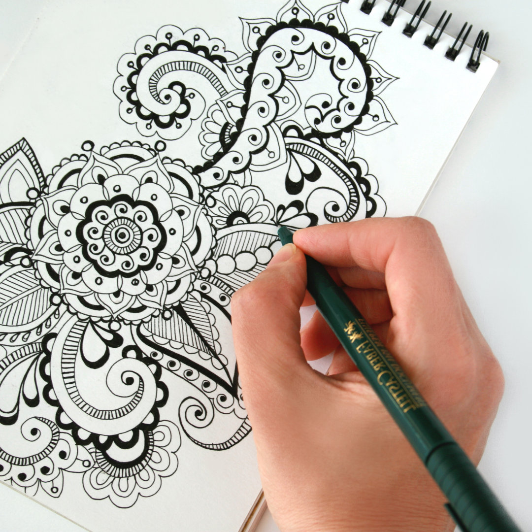 Hand holding a pen, drawing a geometric design
