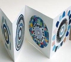 Image of an art journal with blue circles on white paper standing on edge