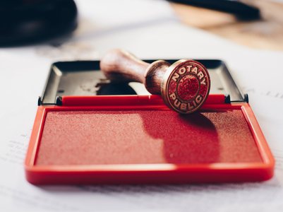 Image of a notary stamp on top of a ink pad with red lid