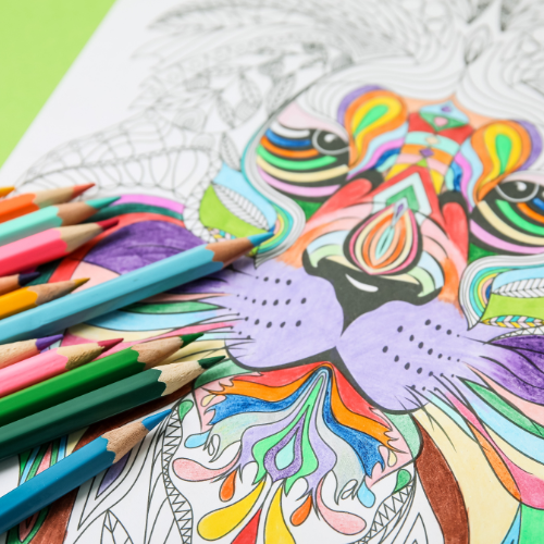 Image of coloring pencils on top of a colorful lion drawing with green background