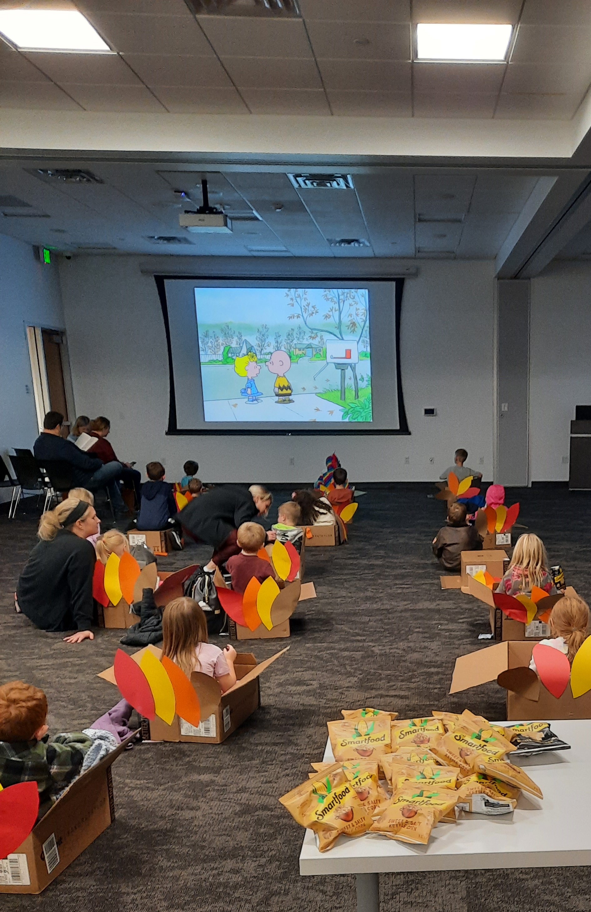 Image of kids watching a movie while sitting in boxes decorated like turkeys