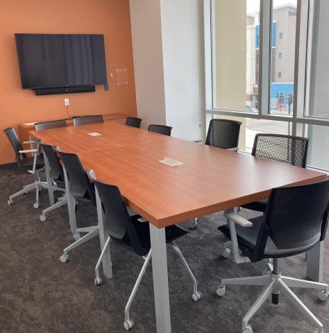 Image of Conference Room D with board table, 10 chairs, mounted television screen