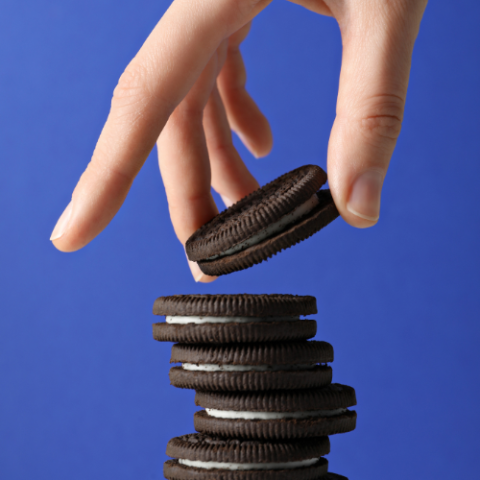 A hand stacking Oreo cookies