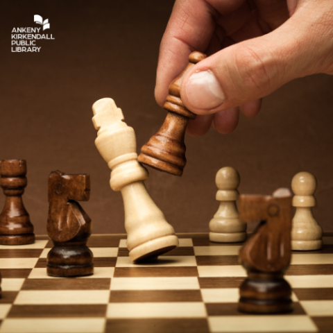 Photo of a chess board with a hand moving a pawn