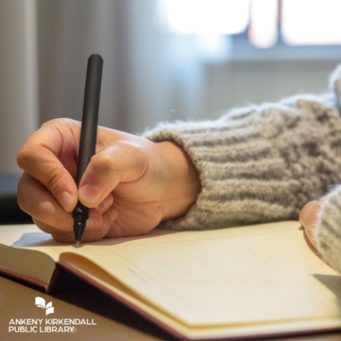 Person in grey sweater writing in a journal