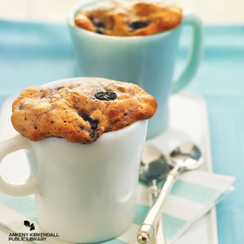 A white and blue mug with blueberry muffins