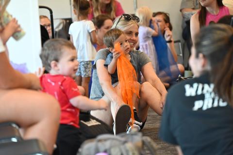Babies, toddlers, and caregivers are laughing at a baby lap-sit event.
