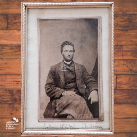 Old photo black and white photo of a man sitting with a background of wood slats