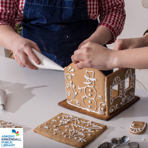 Two people working together to build a gingerbread house