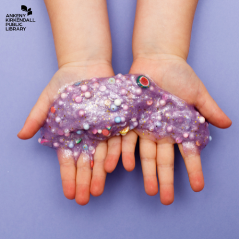 Two hands holding purple slime with beads in it