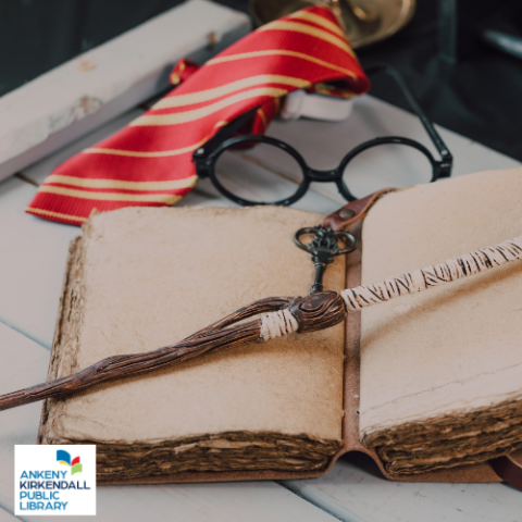 Blank leatherbound journal with a wooden wand and black key on top of it and a red tie and black glasses behind on a desk