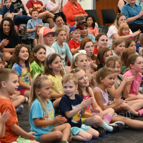 Children are listening to music at a library concert.