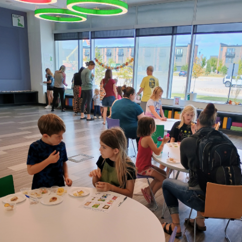 Children and caregivers are eating food in the library.