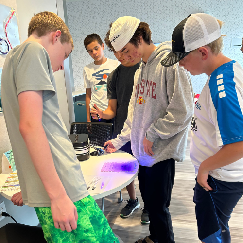 Teens standing around a table, shining a black light