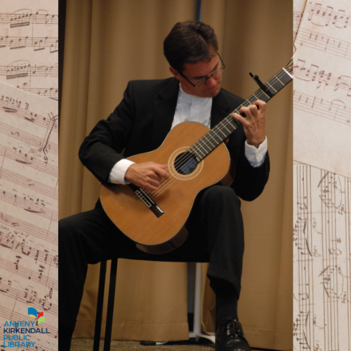 Photo of Peter Fletcher playing guitar with sheets of music as the background