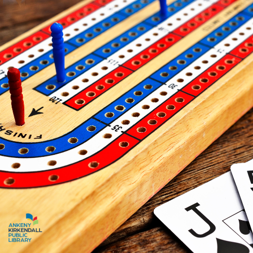 Close up photo of a cribbage board with playing cards in the bottom right corner