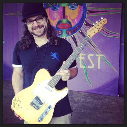 Photo of Joey Leone holding a yellow acoustic guitar