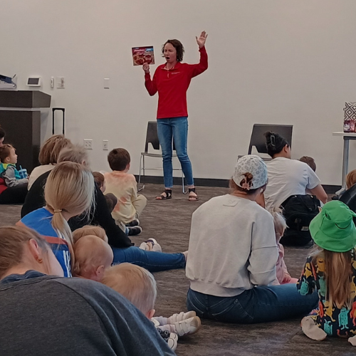 An educator reads a book to a group of people. 