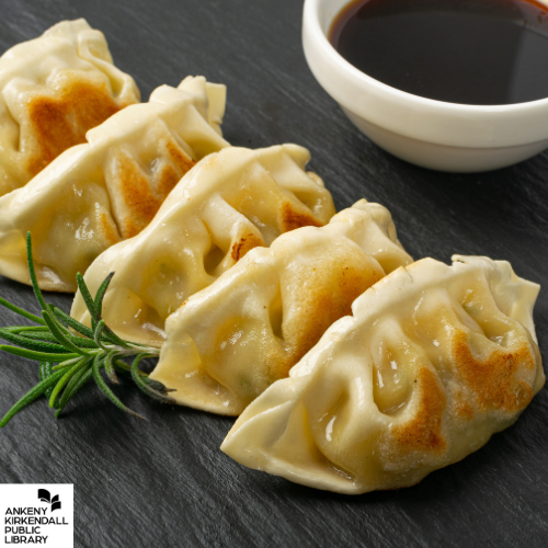 Row of fresh dumplings with a small jar of soy sauce and the Ankeny Kirkendall Public Library logo